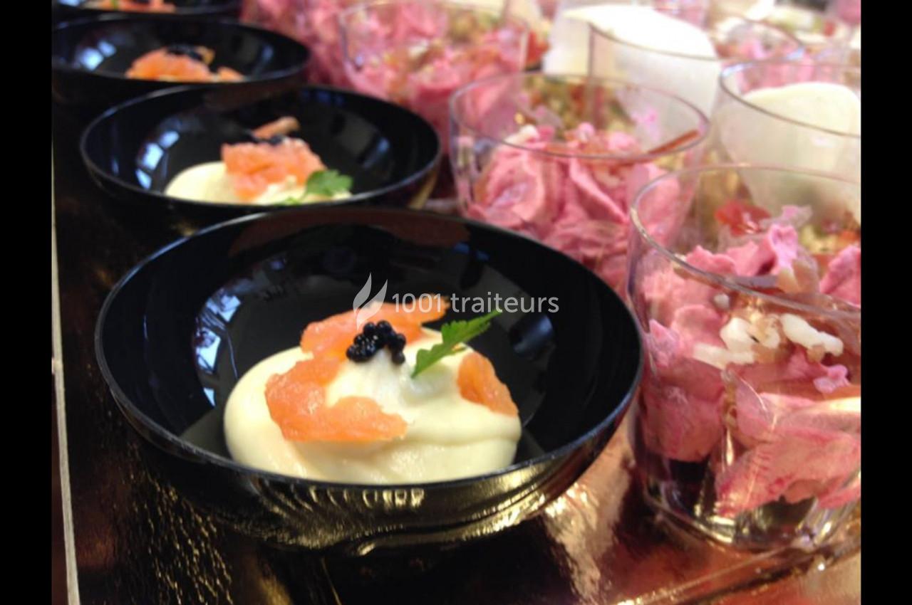 Assortiment de verrines avec mousse rose et bols de crème garnis de saumon fumé, œufs de poisson et herbes fraîches.