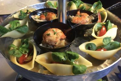 Plateau à étages avec des coquilles garnies de crevettes, légumes et herbes, présenté sur une table de buffet.