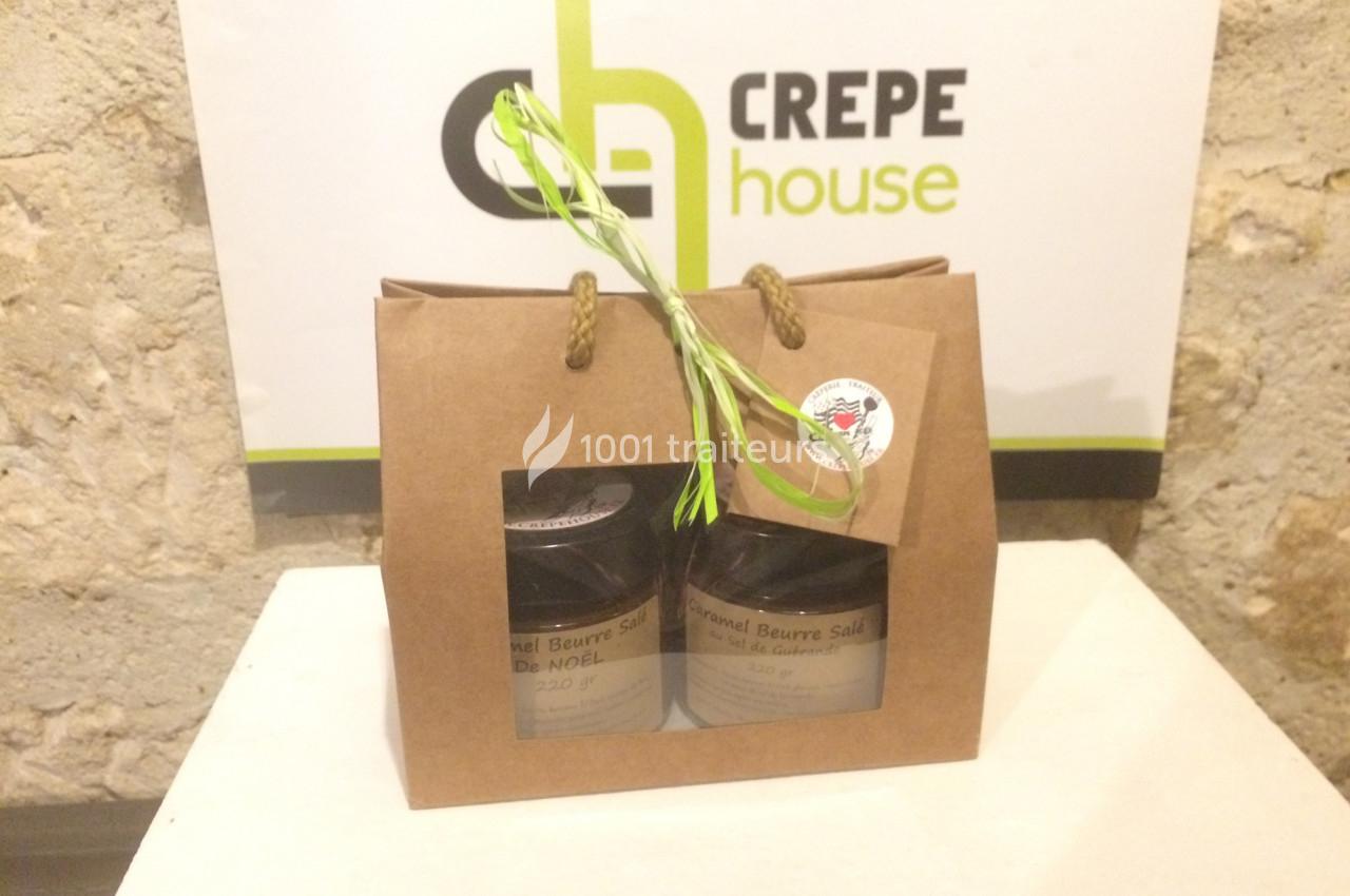 Deux pots de caramel beurre salé dans un sac en papier avec une poignée, posés sur une table devant un mur.