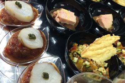 Plateau à étages avec des coquilles garnies de crevettes, légumes et herbes, présenté sur une table de buffet.