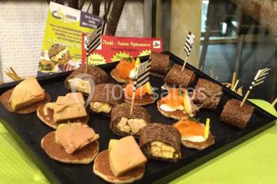 Plateau à étages avec des coquilles garnies de crevettes, légumes et herbes, présenté sur une table de buffet.