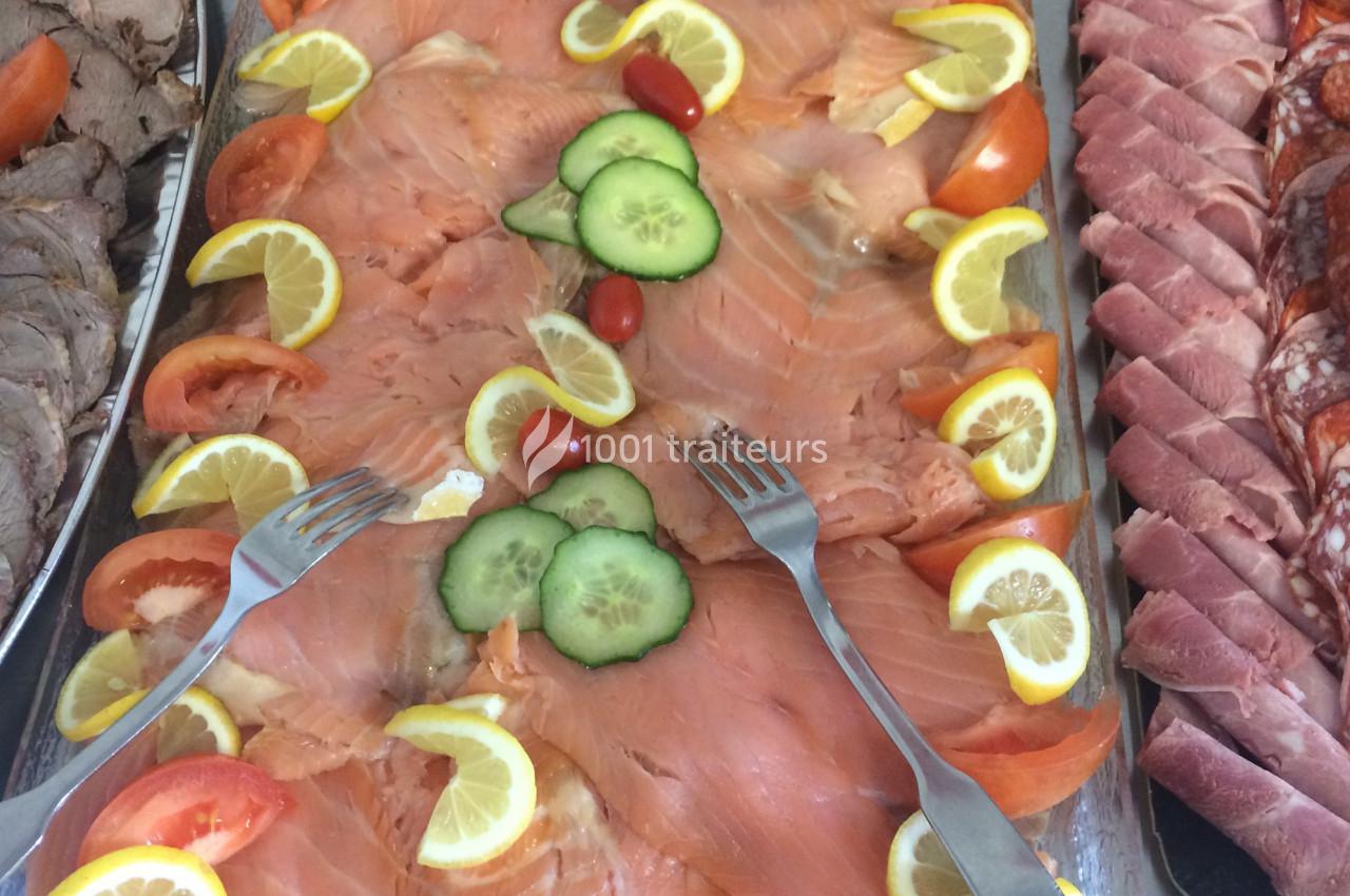 Plateau de saumon fumé garni de tranches de citron, tomates, concombres et tomates cerises, avec deux fourchettes.