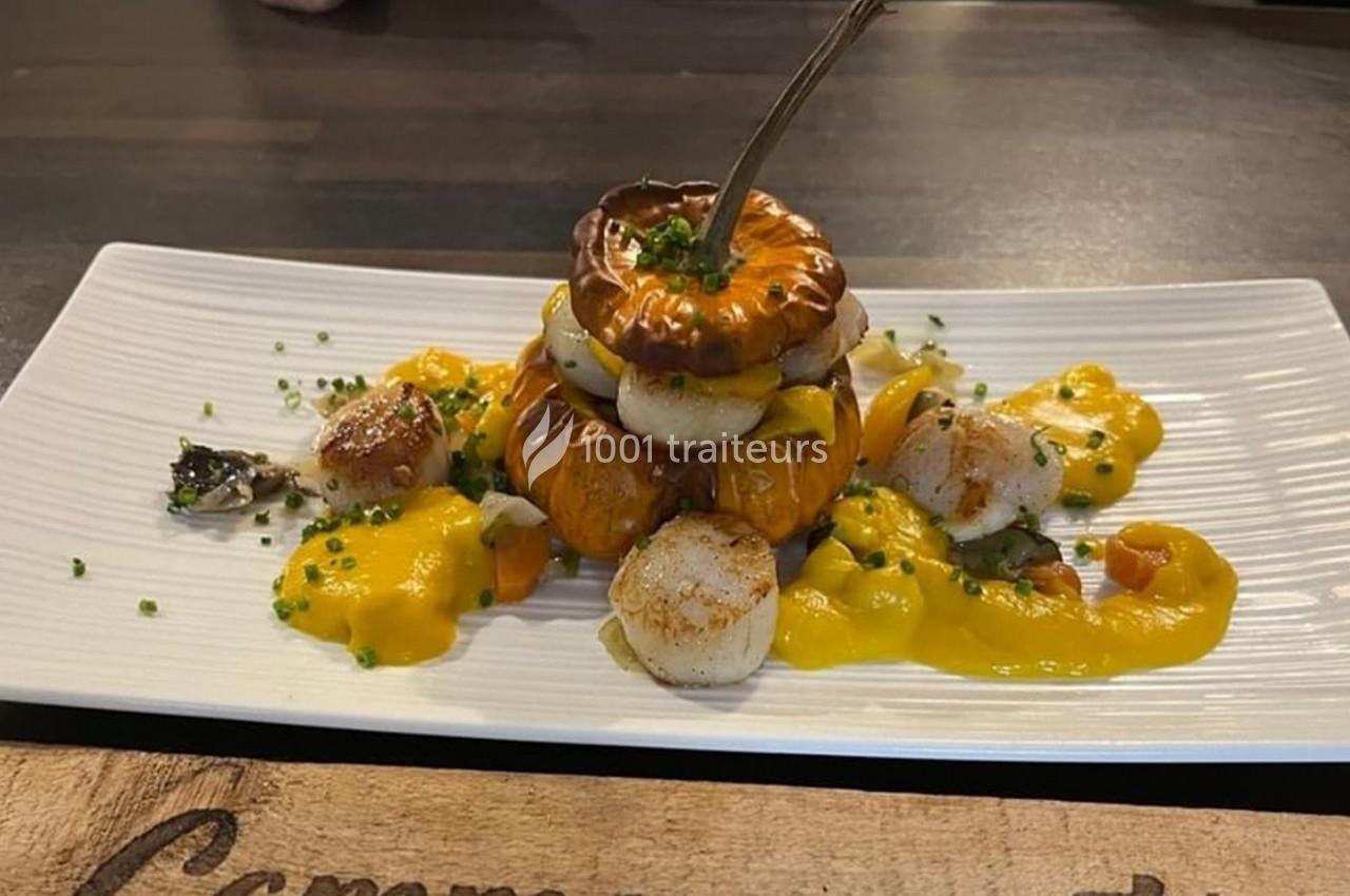 Assiette gastronomique composée de noix de Saint-Jacques, sauce jaune et légumes, présentée sur une assiette blanche.
