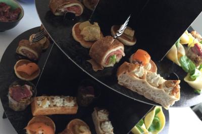 Plateau à étages avec des coquilles garnies de crevettes, légumes et herbes, présenté sur une table de buffet.