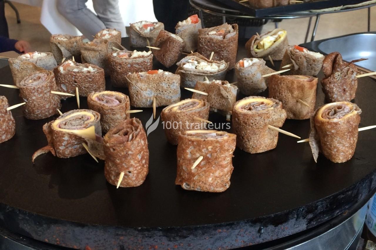 Roulés de galettes de sarrasin garnis, maintenus par des piques, présentés sur une plaque de cuisson.