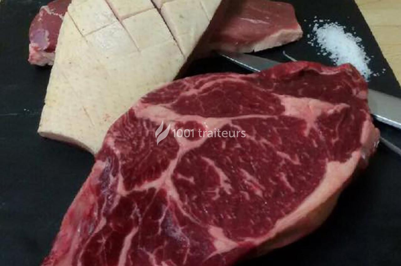 Tranche de viande rouge marbrée, magret de canard incisé et sel sur une planche noire avec un couteau.