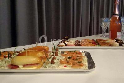 Plateau de mini-burgers colorés et assortiments de canapés sur une table dressée pour un buffet.