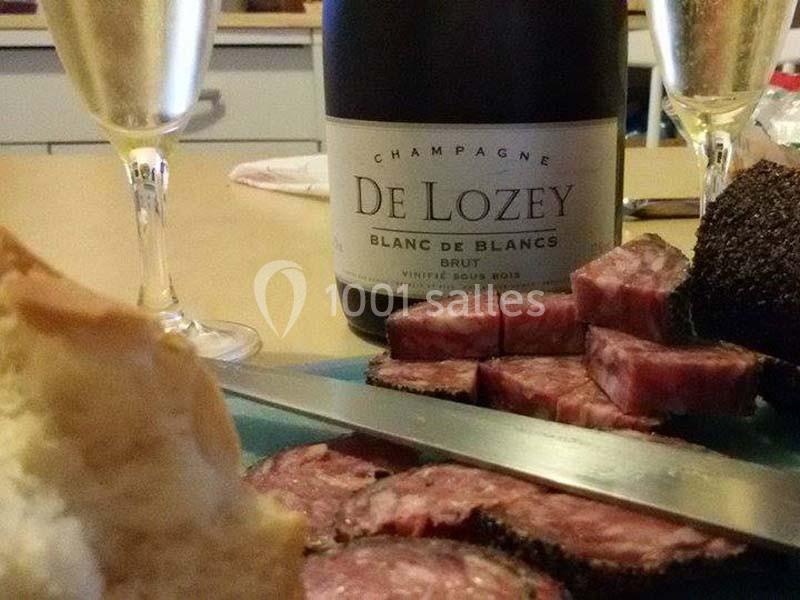 Bouteille de champagne, verres remplis et plateau de charcuterie avec pain sur une table.