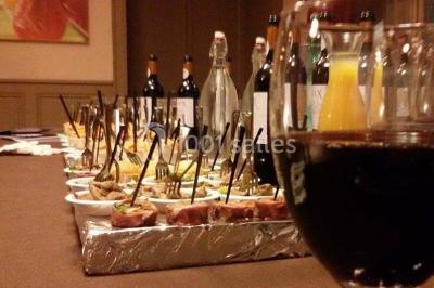 Plateau de mini-burgers colorés et assortiments de canapés sur une table dressée pour un buffet.