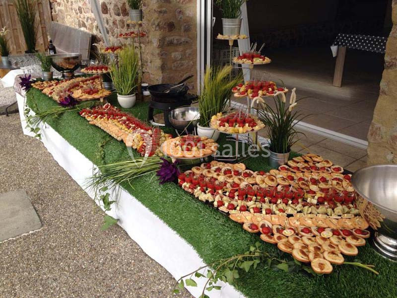 Buffet de réception en extérieur avec une variété de bouchées salées et sucrées disposées sur une table décorée.
