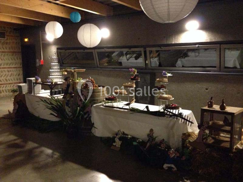 Table décorée pour un buffet avec desserts, présentoirs et lanternes suspendues dans une salle à l'éclairage tamisé.