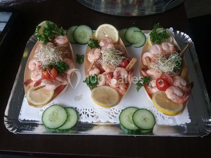 Assiettes garnies de crevettes, rondelles de citron, tomates cerises, germes et persil, présentées sur un plateau.