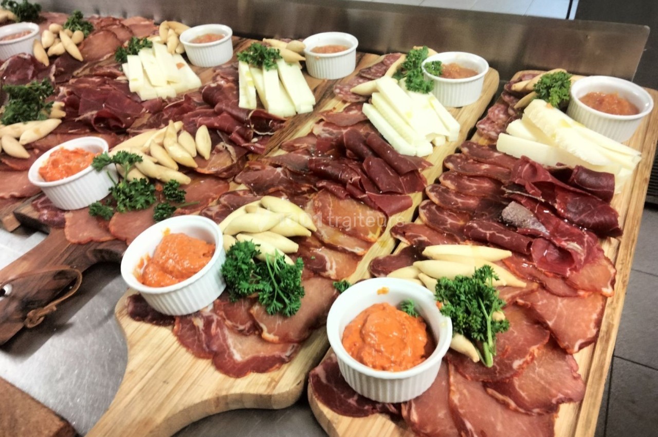 Plateaux de charcuterie variée avec fromages, sauces en ramequins et garniture de persil sur des planches en bois.