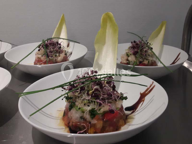 Assiette de tartare de légumes et crevettes, garnie de jeunes pousses, ciboulette et feuille d'endive.