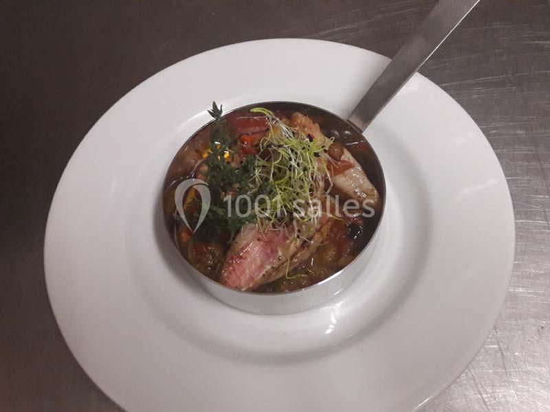 Plat de poisson dressé dans une assiette blanche, accompagné de légumes, herbes fraîches et pousses décoratives.