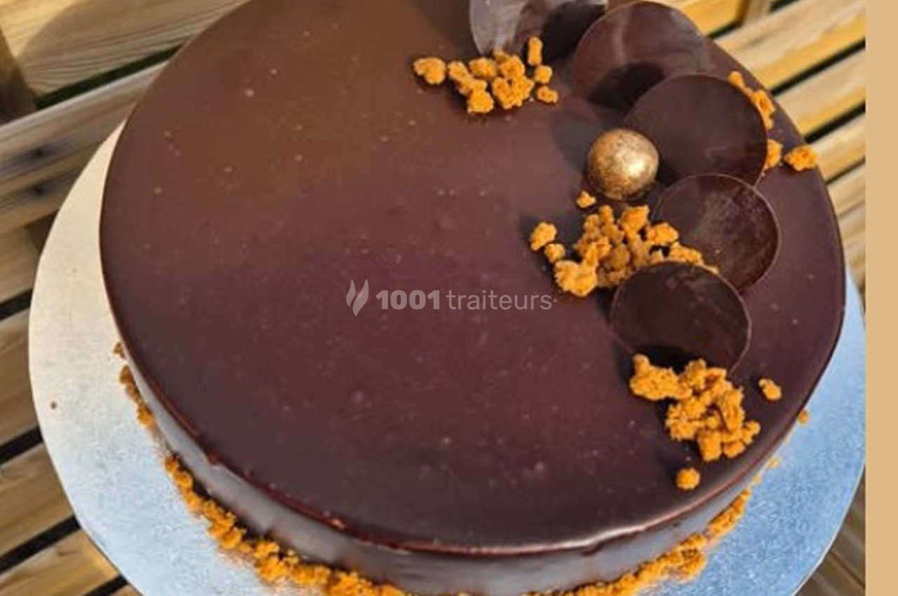 Gâteau au glaçage chocolat brillant, décoré de disques en chocolat, miettes croustillantes et une perle dorée.