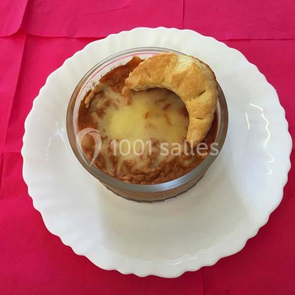 Gratin de haricots rouges au fromage dans un ramequin, accompagné d'un croissant, sur une assiette blanche.