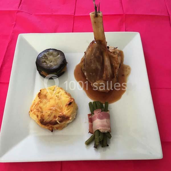 Assiette composée d'un jarret d'agneau en sauce, d'un gratin, d'une tranche d'aubergine et de haricots verts enroulés de…