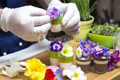 Tour de coupes en verre illuminée et gâteau à étages décoré de fleurs roses sur une table de réception.