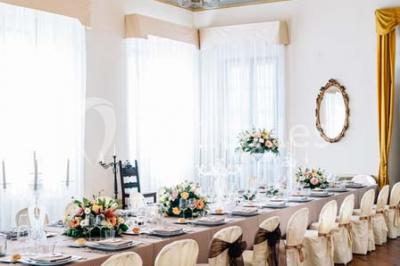 Tour de coupes en verre illuminée et gâteau à étages décoré de fleurs roses sur une table de réception.