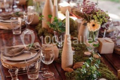 Tour de coupes en verre illuminée et gâteau à étages décoré de fleurs roses sur une table de réception.