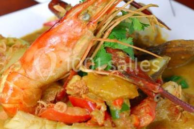 Tour de coupes en verre illuminée et gâteau à étages décoré de fleurs roses sur une table de réception.