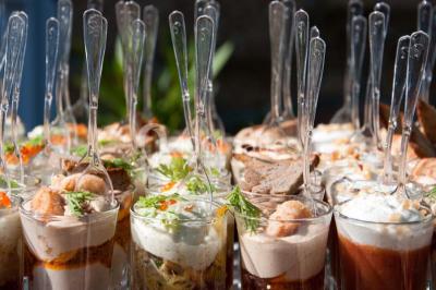 Tour de coupes en verre illuminée et gâteau à étages décoré de fleurs roses sur une table de réception.