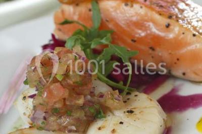 Tour de coupes en verre illuminée et gâteau à étages décoré de fleurs roses sur une table de réception.