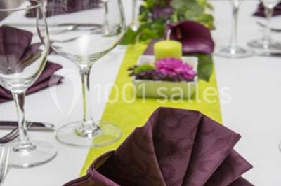 Tour de coupes en verre illuminée et gâteau à étages décoré de fleurs roses sur une table de réception.