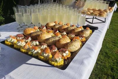 Tour de coupes en verre illuminée et gâteau à étages décoré de fleurs roses sur une table de réception.