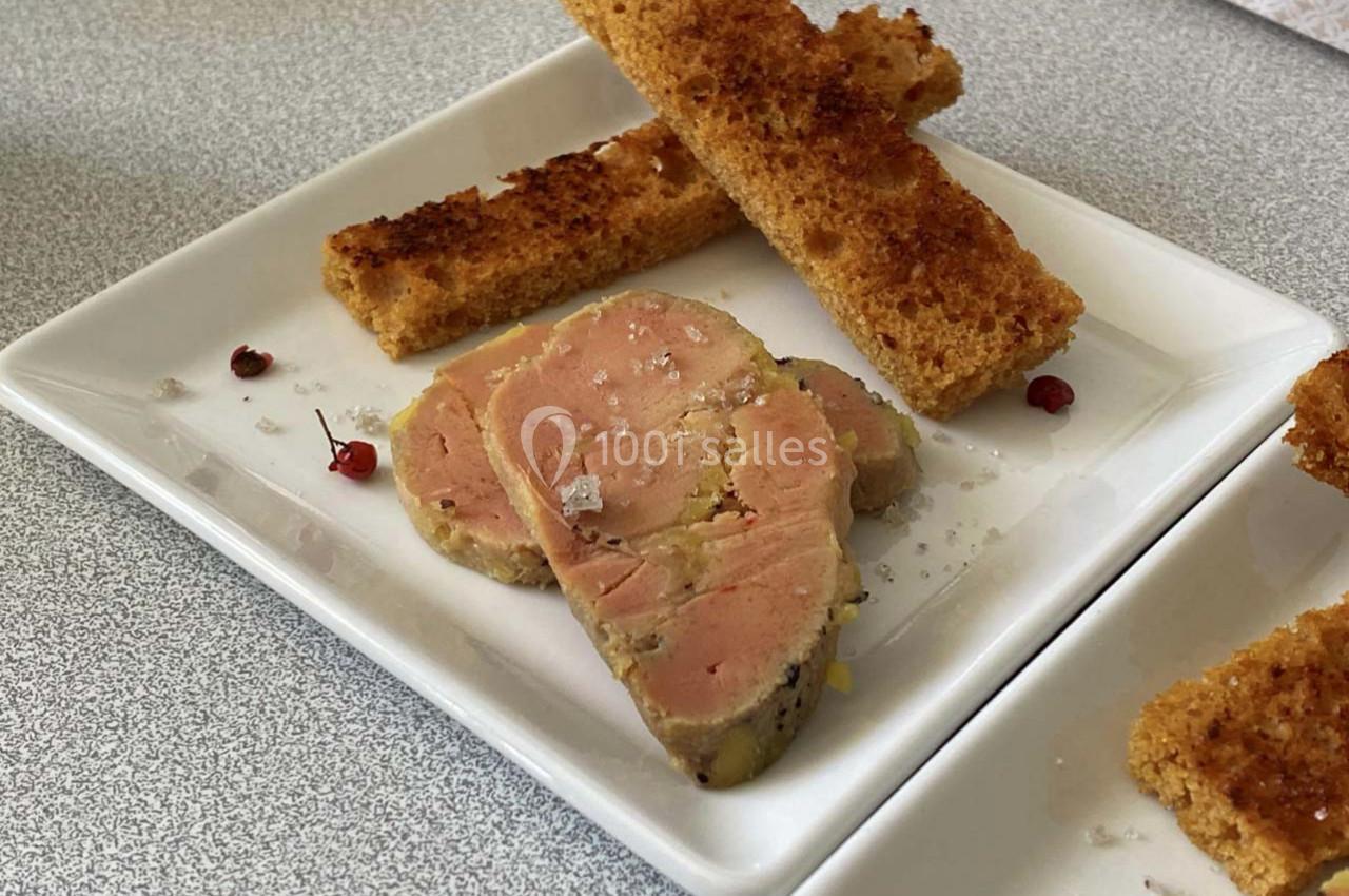 Tranches de foie gras sur une assiette blanche, accompagnées de toasts dorés et de quelques grains de sel.