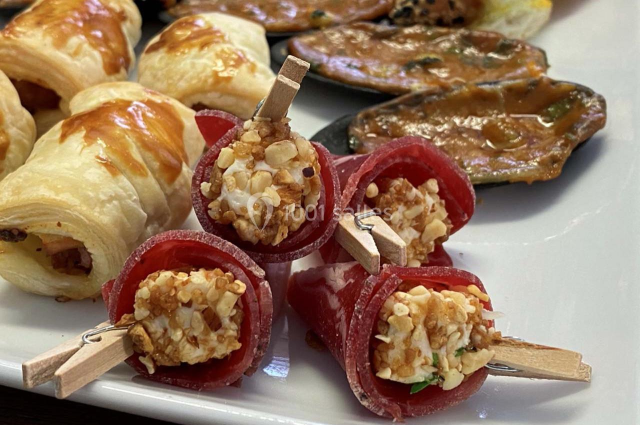 Assortiment d'amuse-bouches comprenant roulés au fromage, feuilletés dorés et moules gratinées sur un plateau.