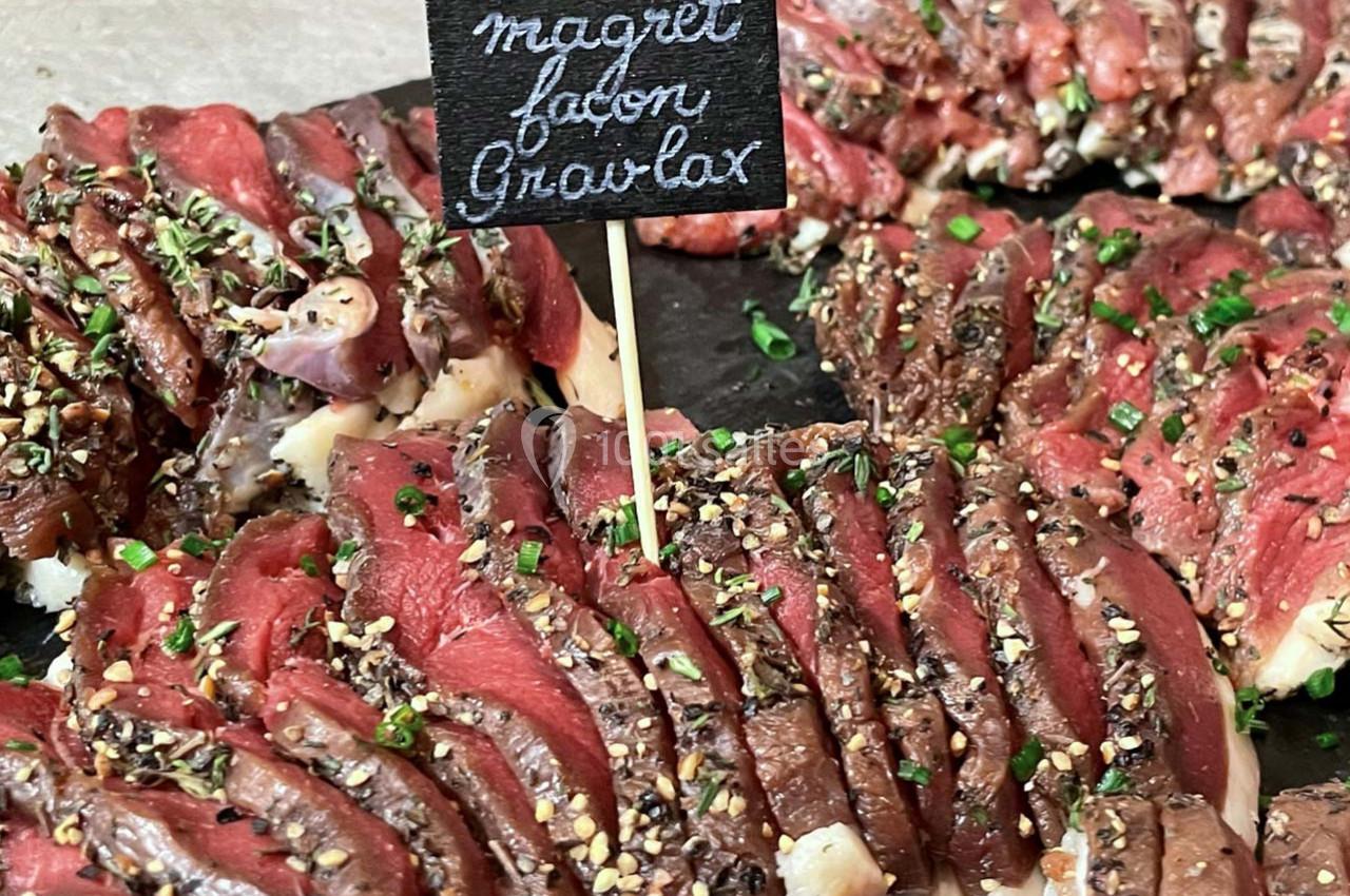 Tranches de magret de canard façon gravlax, assaisonnées d'herbes et d'épices, présentées sur un plateau.