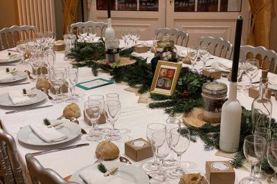 Table décorée pour un repas festif avec nappes blanches, verres, bougies, décorations végétales et petits cadeaux.