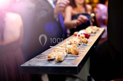 Cuisine professionnelle avec plans de travail en inox, évier, robinet flexible et porte de sortie au fond.