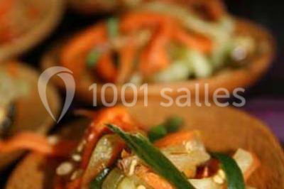 Cuisine professionnelle avec plans de travail en inox, évier, robinet flexible et porte de sortie au fond.