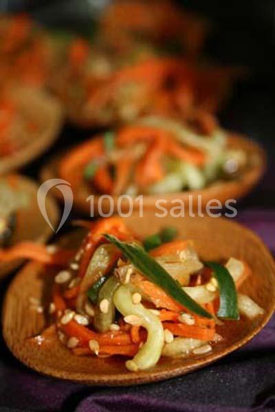 Assiette en bois contenant une salade de légumes croquants avec carottes, concombres, graines et oignons verts.