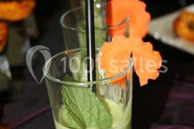 Cuisine professionnelle avec plans de travail en inox, évier, robinet flexible et porte de sortie au fond.