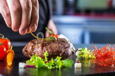 Cuisine professionnelle avec plans de travail en inox, évier, robinet flexible et porte de sortie au fond.