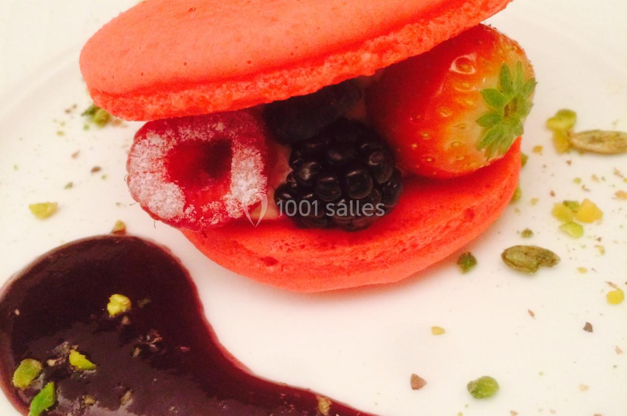 Macaron rouge garni de fruits rouges et noirs, décoré de groseilles, pistaches concassées et coulis de fruits.