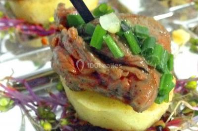 Cuisine professionnelle avec plans de travail en inox, évier, robinet flexible et porte de sortie au fond.