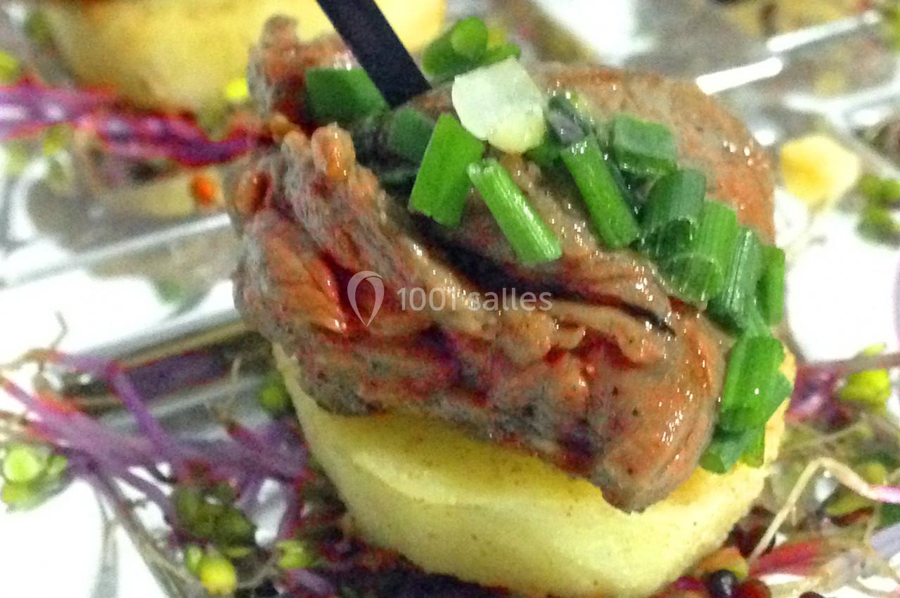 Bouchée apéritive composée de viande garnie de ciboulette sur une base de pomme de terre et jeunes pousses.