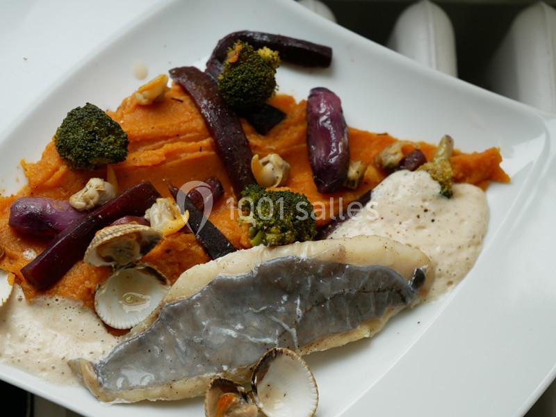 Assiette composée de purée de patate douce, légumes rôtis, poisson et coquillages, accompagnée d'une sauce crémeuse.