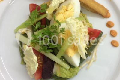 Bol de farine, fouet métallique, citrons, zesteur, beurre et noisettes posés sur une planche en bois.