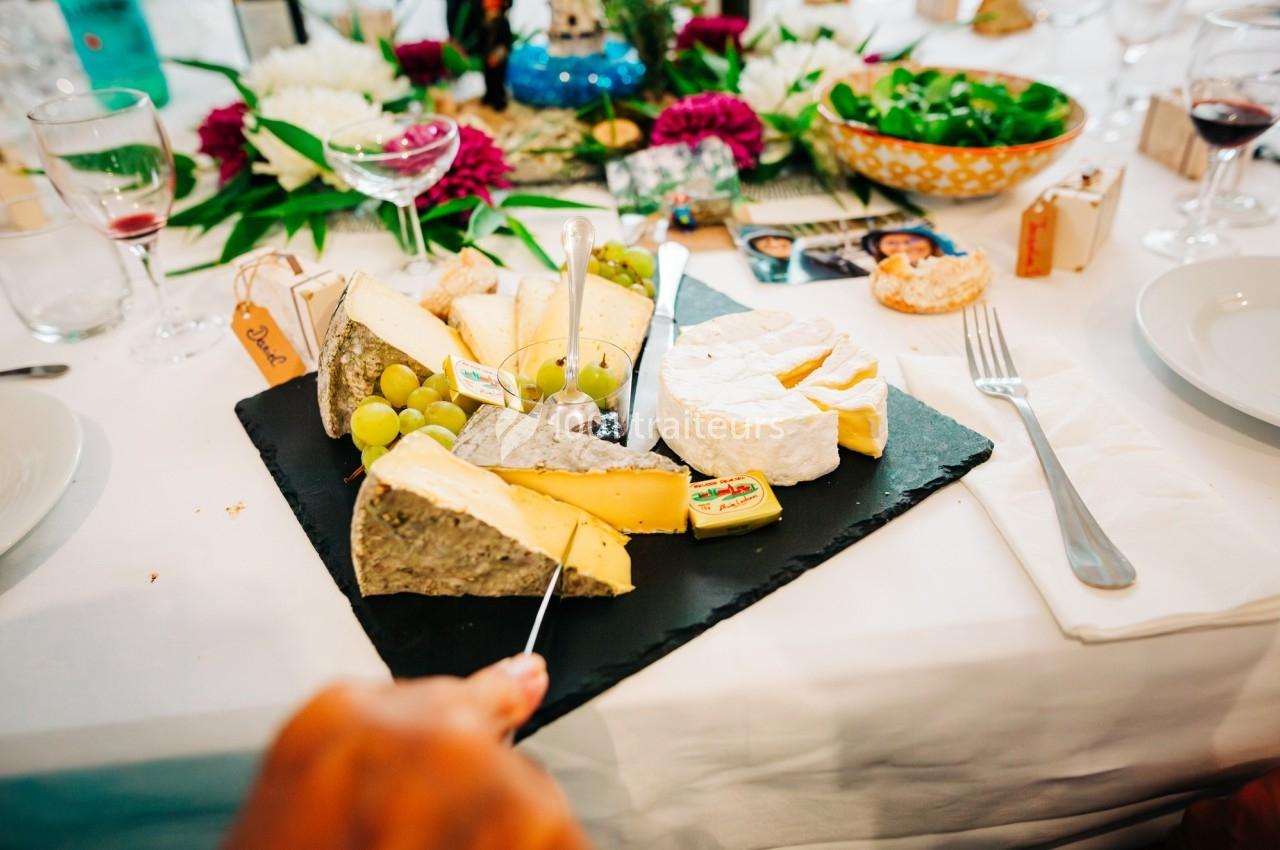 Plateau de fromages variés avec raisins et couteau, disposé sur une table dressée pour un repas convivial.