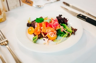 Bol de farine, fouet métallique, citrons, zesteur, beurre et noisettes posés sur une planche en bois.