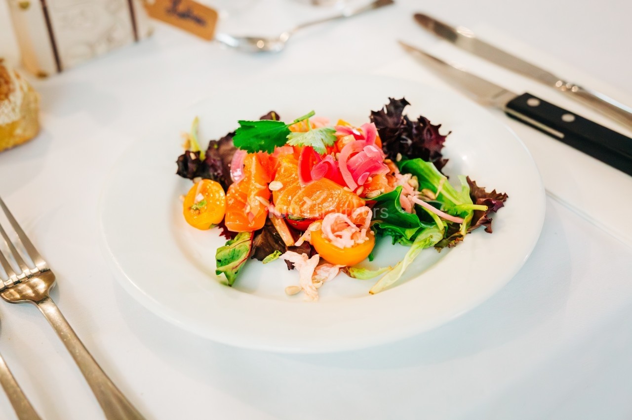 Assiette de salade colorée avec tomates cerises, feuilles de salade, légumes marinés et herbes fraîches.