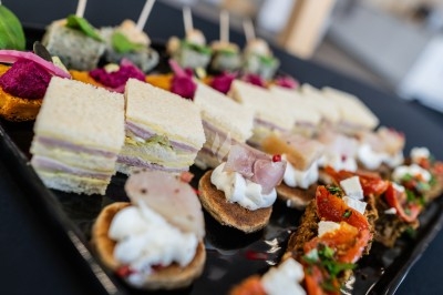 Bol de farine, fouet métallique, citrons, zesteur, beurre et noisettes posés sur une planche en bois.