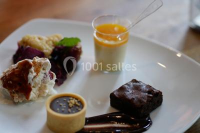 Bol de farine, fouet métallique, citrons, zesteur, beurre et noisettes posés sur une planche en bois.