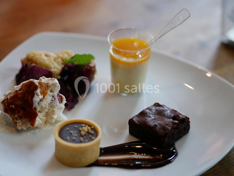 Assortiment de desserts sur une assiette blanche, comprenant mousse, tartelette, brownie et verrine de crème.